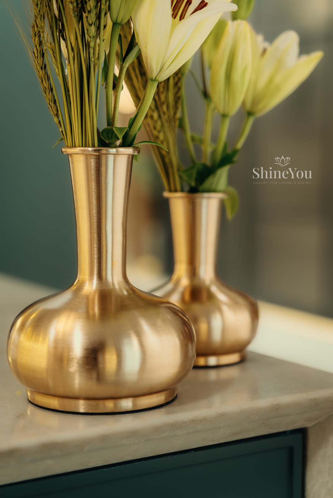 Twin brass vases with lilies on a stone counter